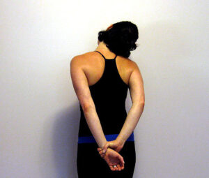 Woman stretching neck, arms behind back.